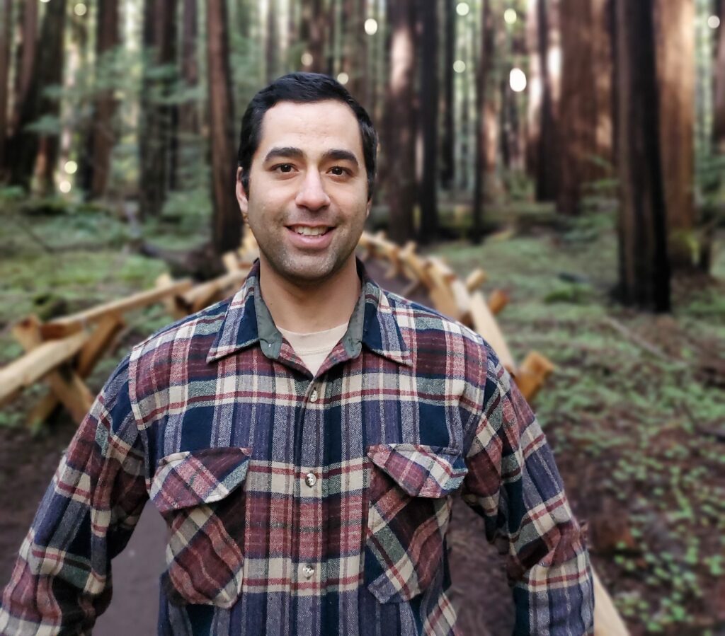 Joshua Canepa Gallo in a flannel shirt standing in a forest